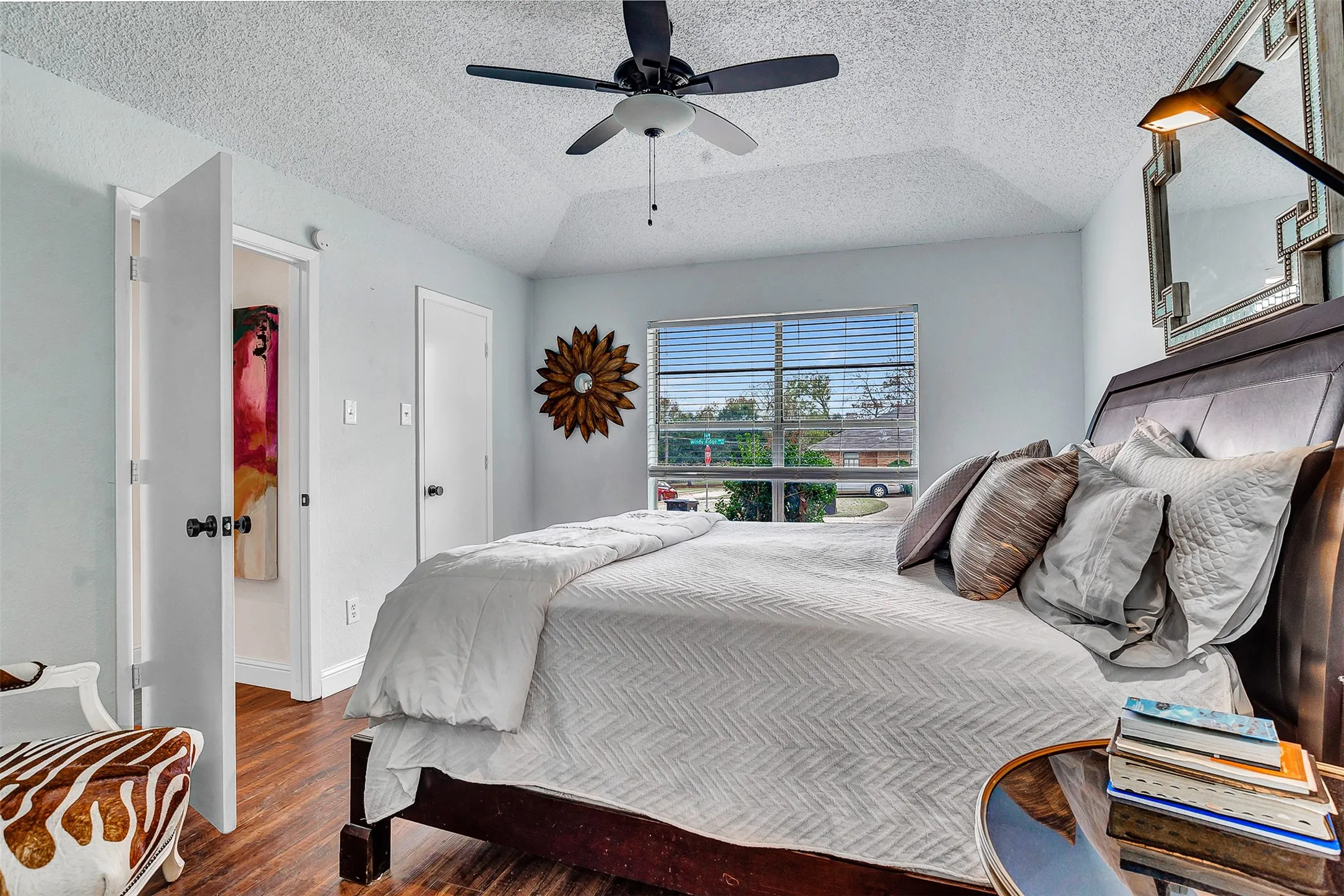 Tray ceiling with a ceiling fan, wood-finish flooring, window with blinds, and white interior doors
