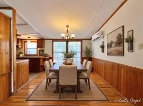 Wood-finish flooring throughout, wood paneling on lower walls, and a multi-light chandelier