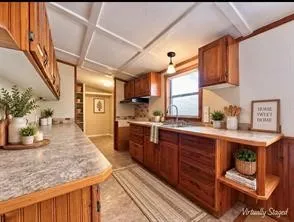 Kitchen featuring wood cabinetry, light-toned countertops, a stainless steel sink, and beadboard paneling