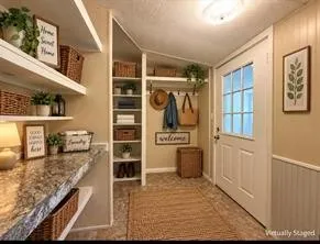 Entryway with a glass paneled door, built-in open shelving, and a patterned countertop