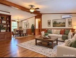 Wood-finish flooring throughout, exposed wood beams, built-in shelving unit, ceiling fan, and wall-mounted climate control unit
