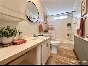Built-in vanity with undermount sink, white cabinetry, and an oval wall-mounted mirror