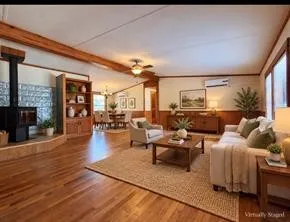 Hardwood-style flooring throughout, exposed wood beams, built-in shelving, a wood-burning stove with a stone surround, and abundant natural light