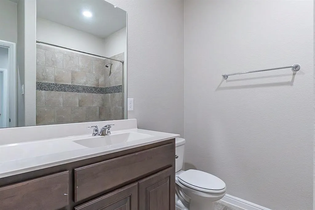 Bathroom with a tile shower, vanity, and toilet