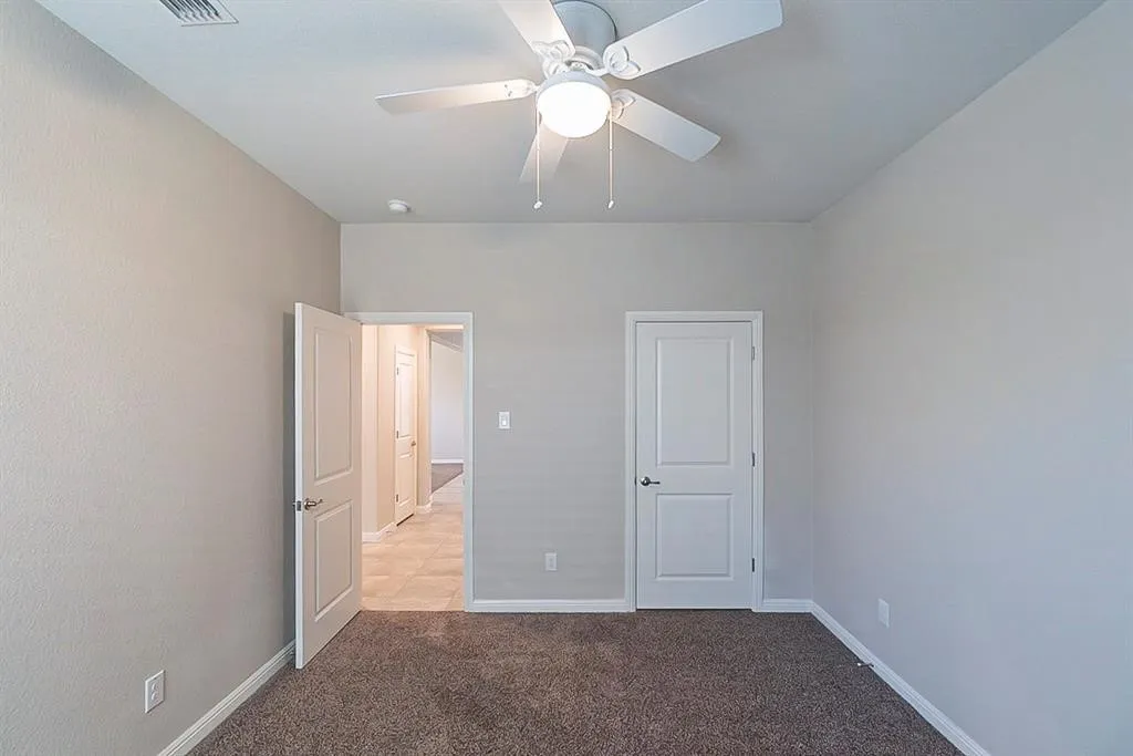Unfurnished bedroom featuring light colored carpet, ceiling fan, and baseboards