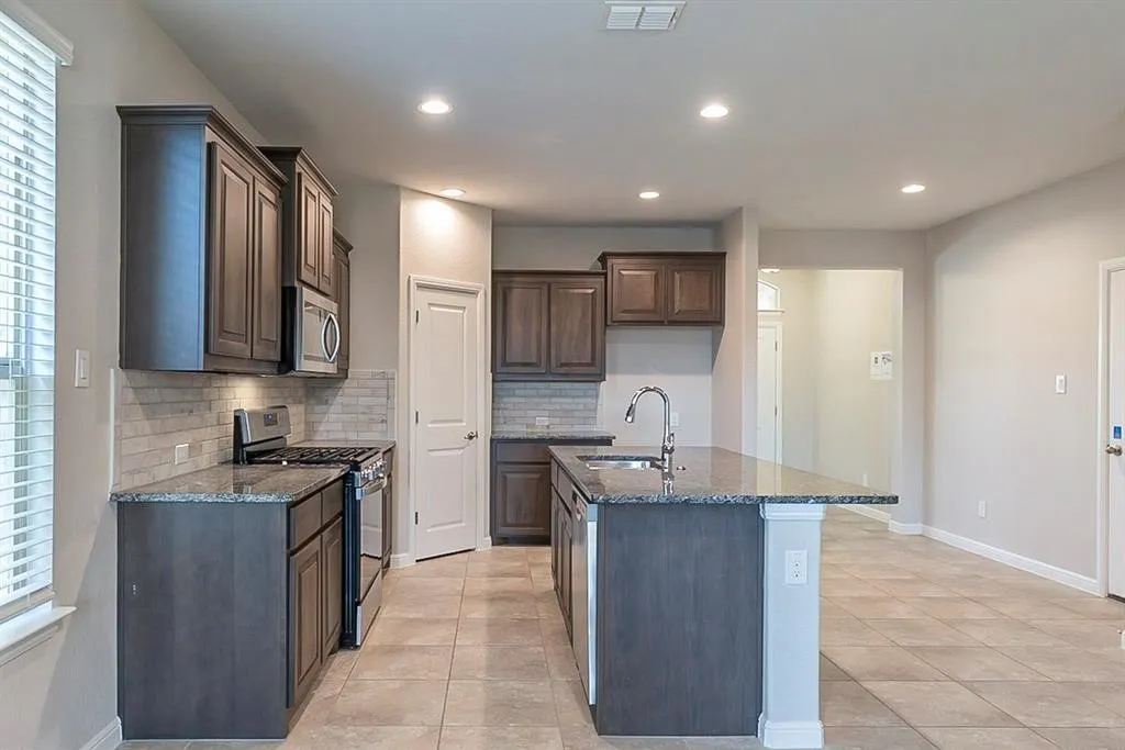 Kitchen featuring visible vents, decorative backsplash, appliances with stainless steel finishes, dark stone countertops, and a sink