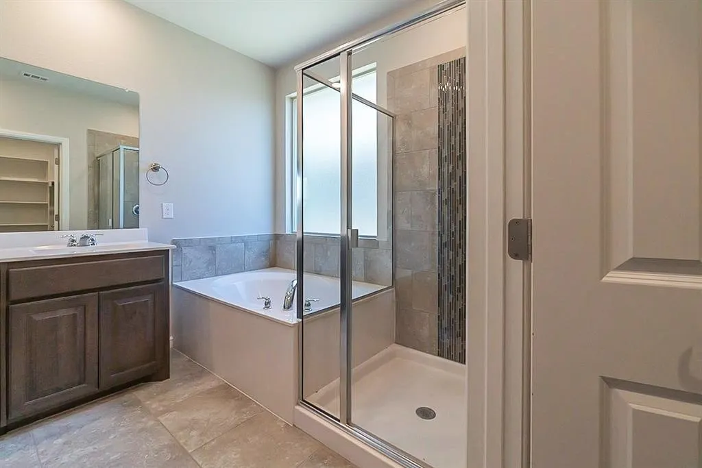Bathroom with a stall shower, a garden tub, and vanity