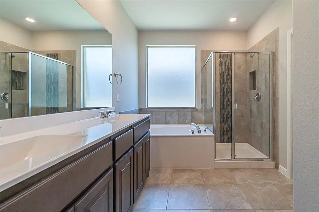 Bathroom featuring a stall shower, a garden tub, a sink, and double vanity