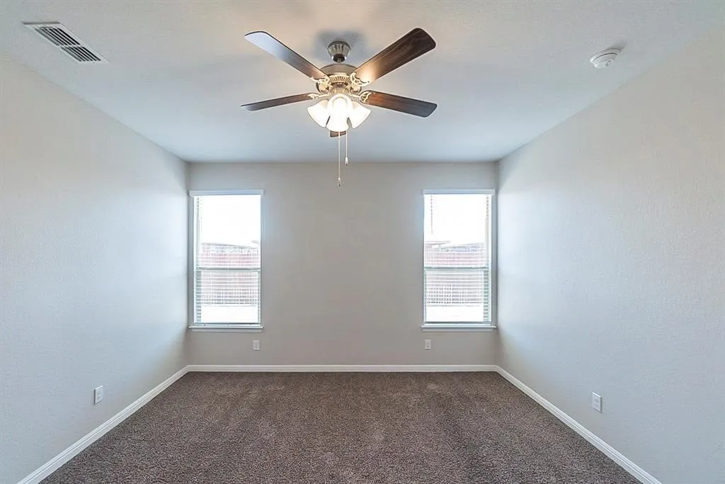 Spare room featuring carpet floors, plenty of natural light, visible vents, and baseboards