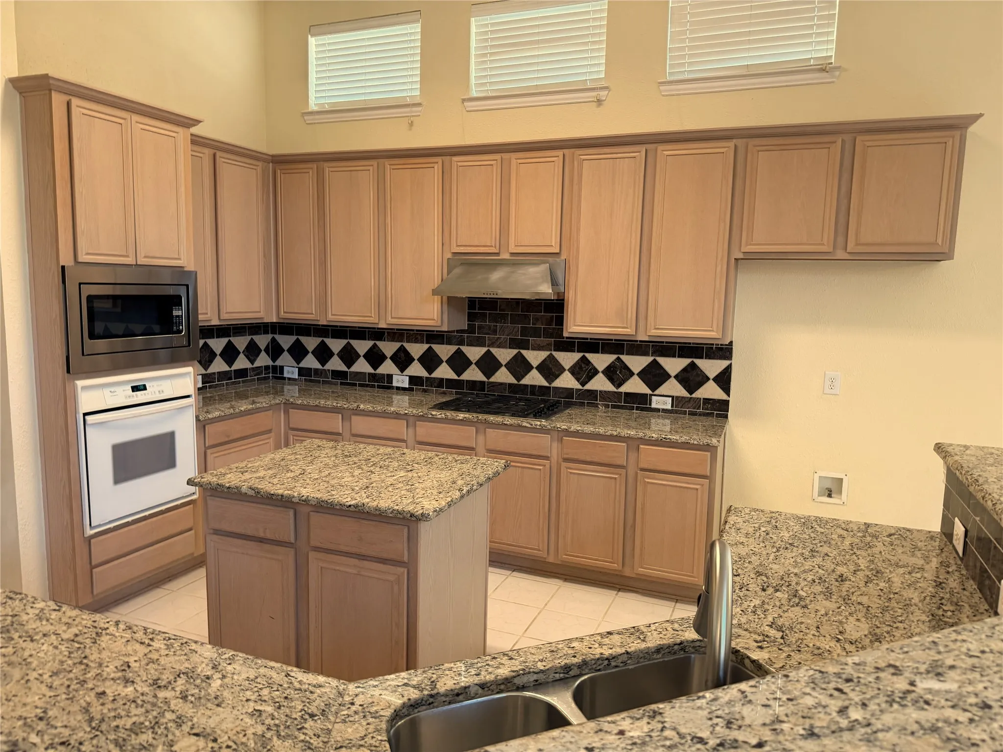 Kitchen featuring granite countertops, wood cabinetry, a built-in microwave, a gas cooktop, and a double basin stainless steel sink