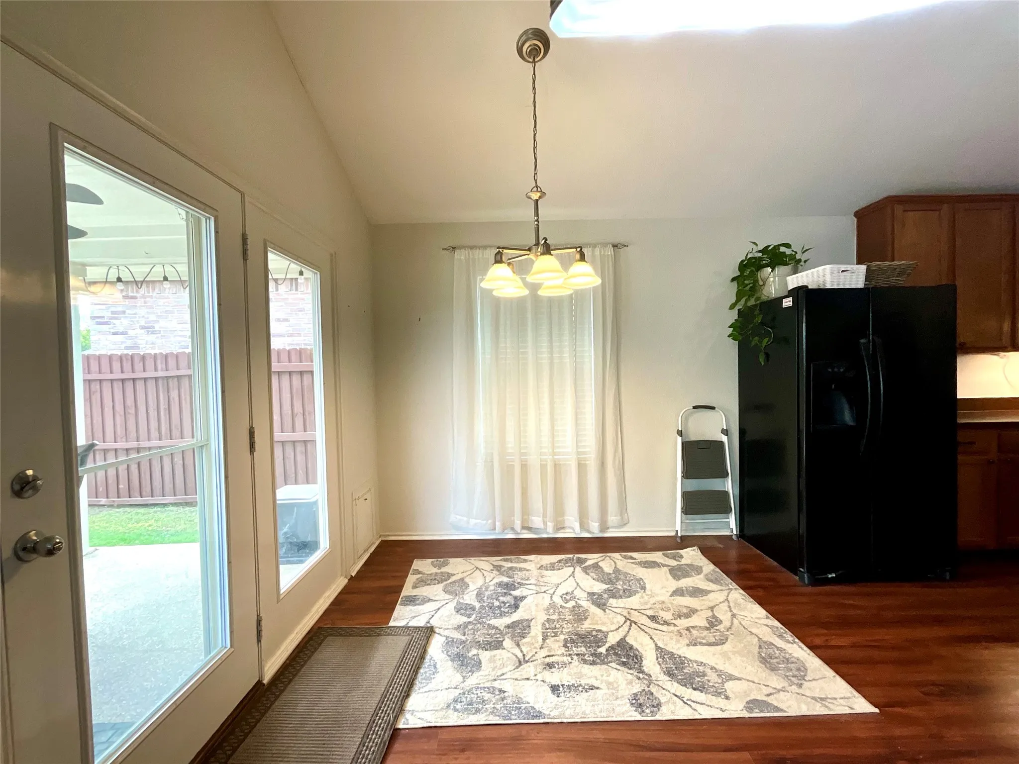 Wood-finish flooring throughout, double-pane glass French doors, and a window with sheer curtains