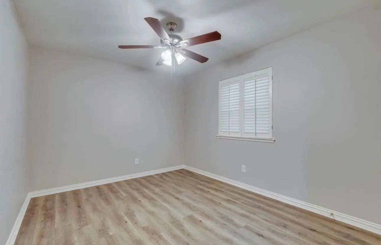 Wood-finish flooring, white plantation shutters, and a ceiling fan with integrated lighting