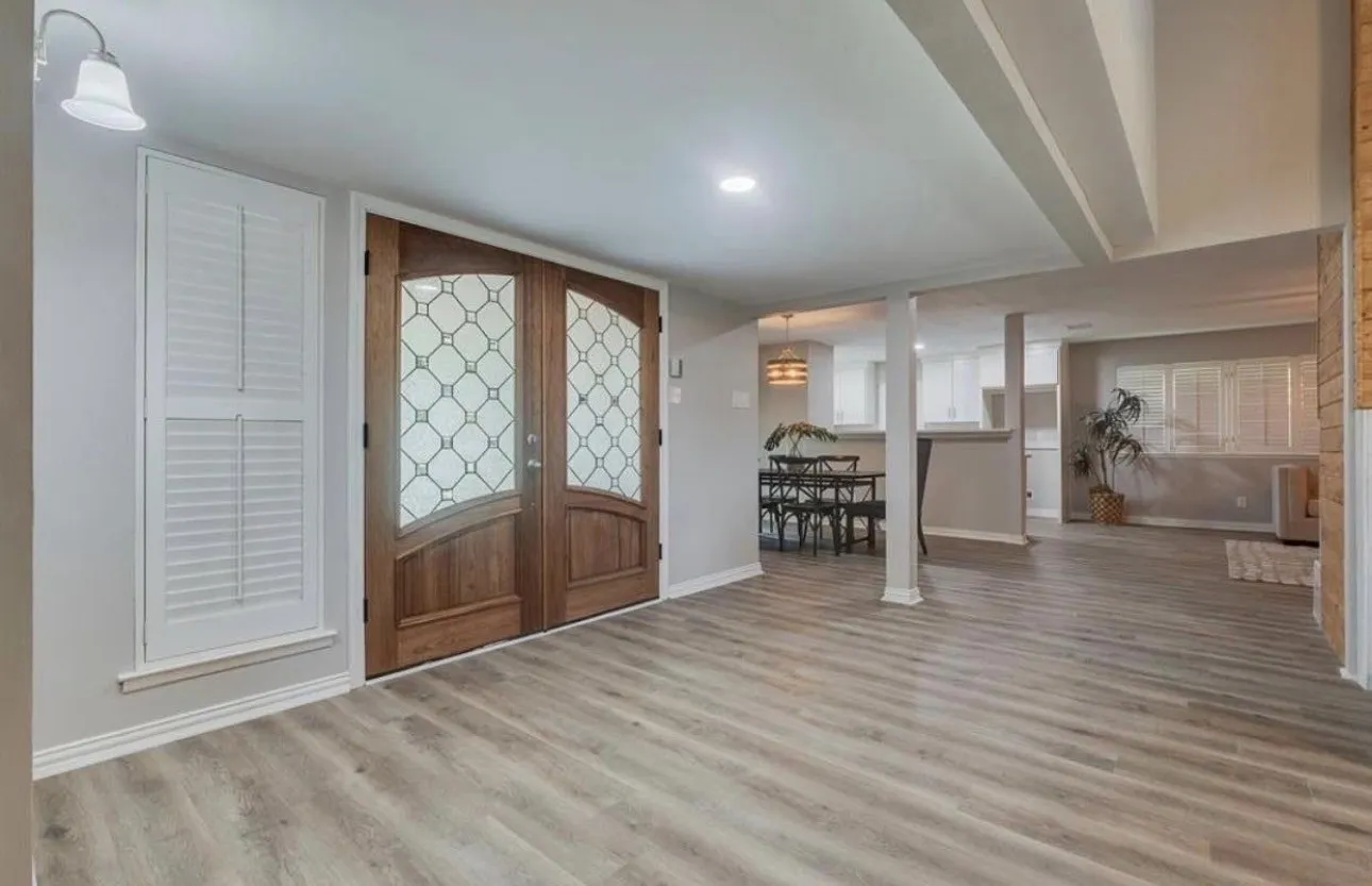 Double entry doors with decorative glass inserts, wood-finish flooring, recessed lighting, and wall-mounted lighting fixture