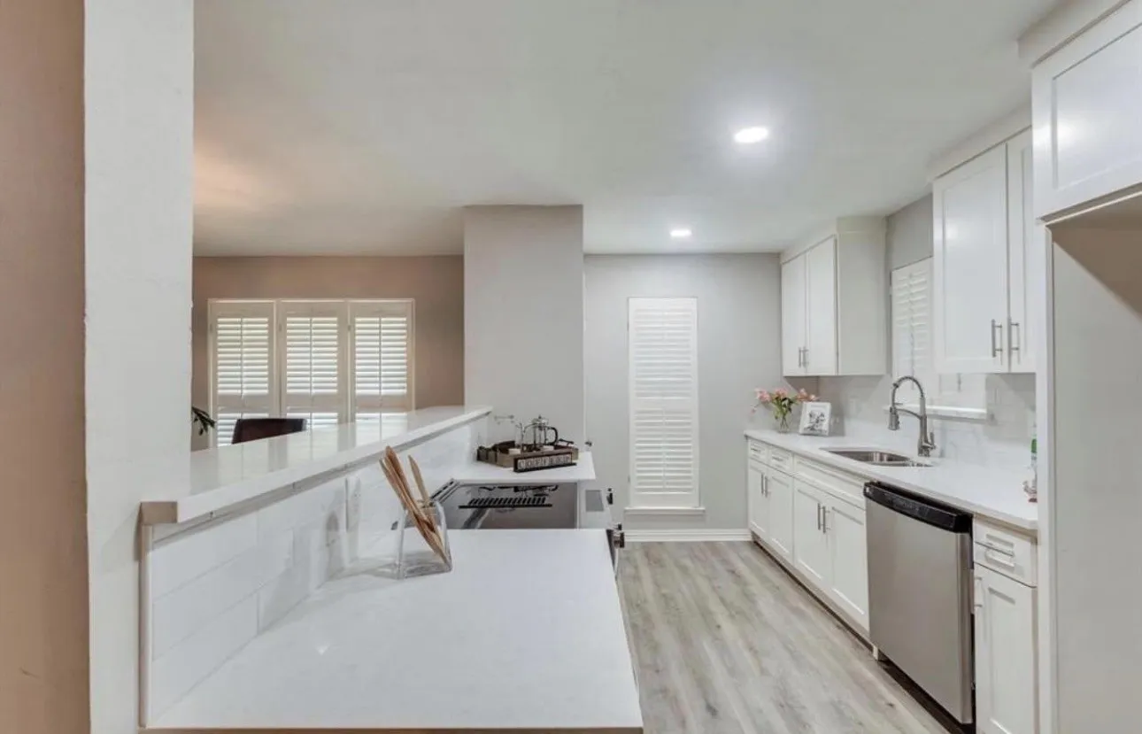 Modern kitchen with white cabinetry, stainless steel dishwasher, undermount sink, and wood-finish flooring