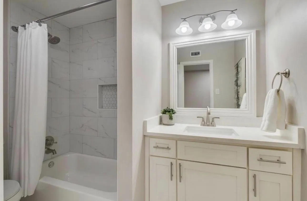 White vanity with brushed nickel hardware, a white undermount sink, and a framed mirror