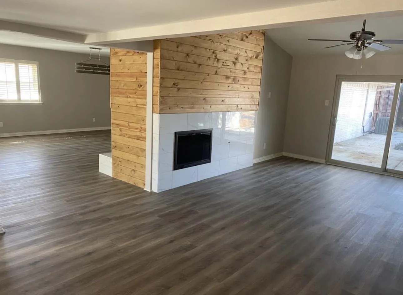 Wood-finish flooring throughout, featuring a fireplace with a wood-paneled and tile surround