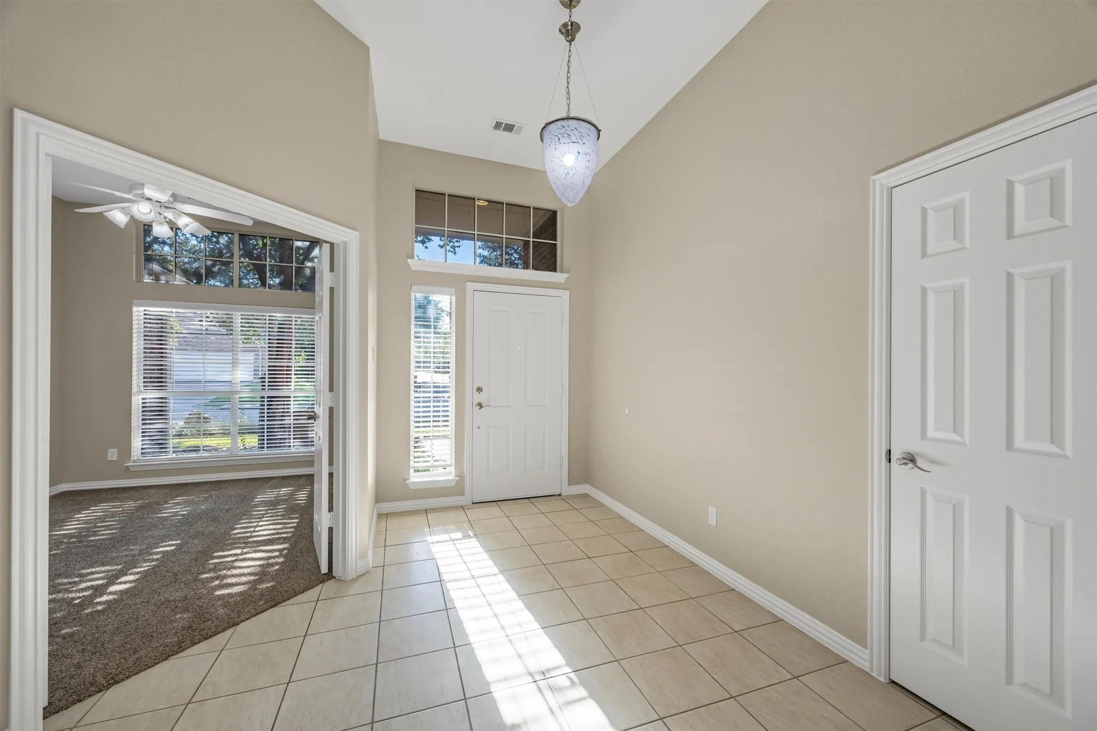 Tiled foyer entry, pendant light, transom window, & storm door.