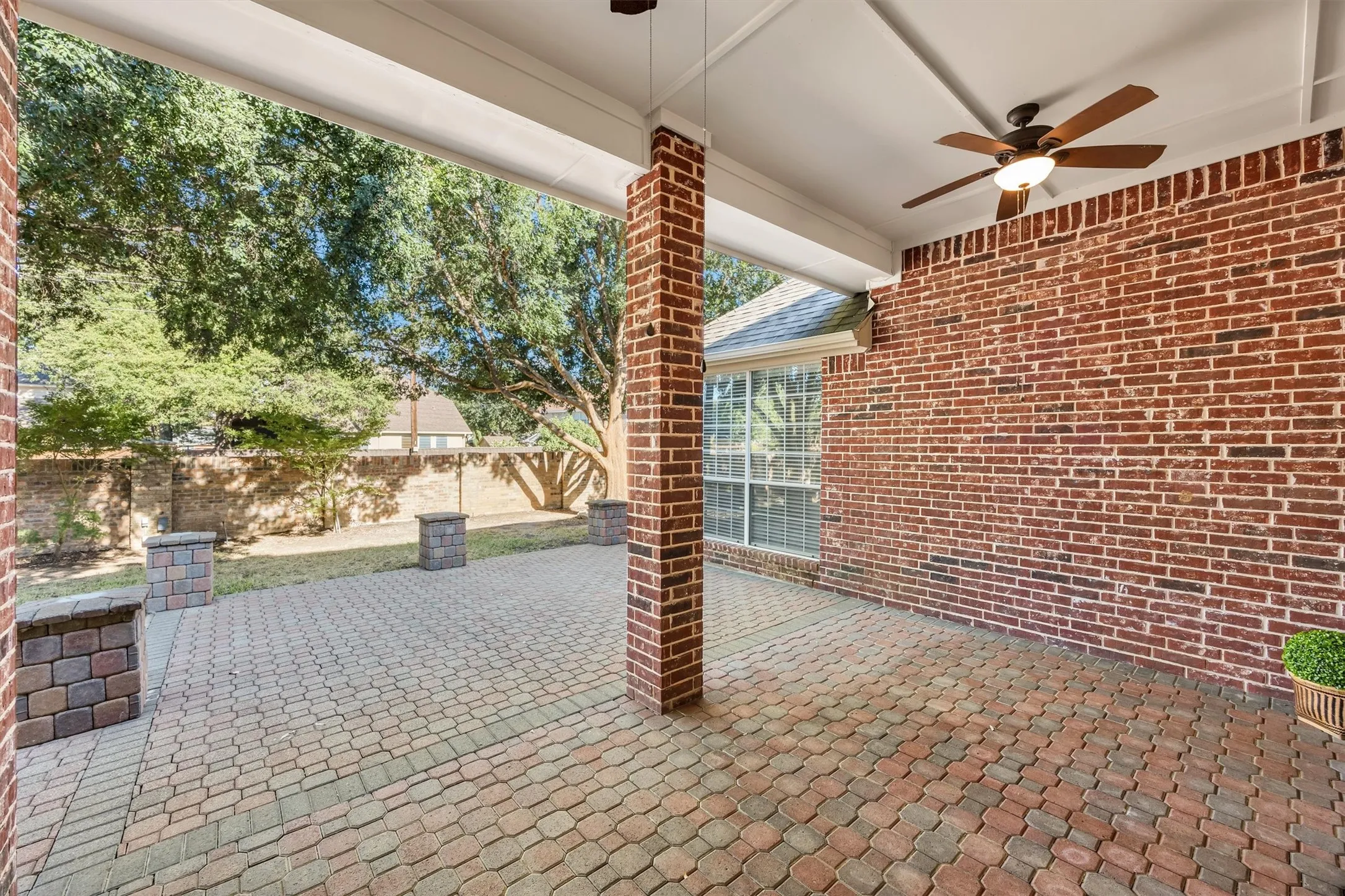 Covered brick patio featuring  2 ceiling fans, and decorative paver flooring