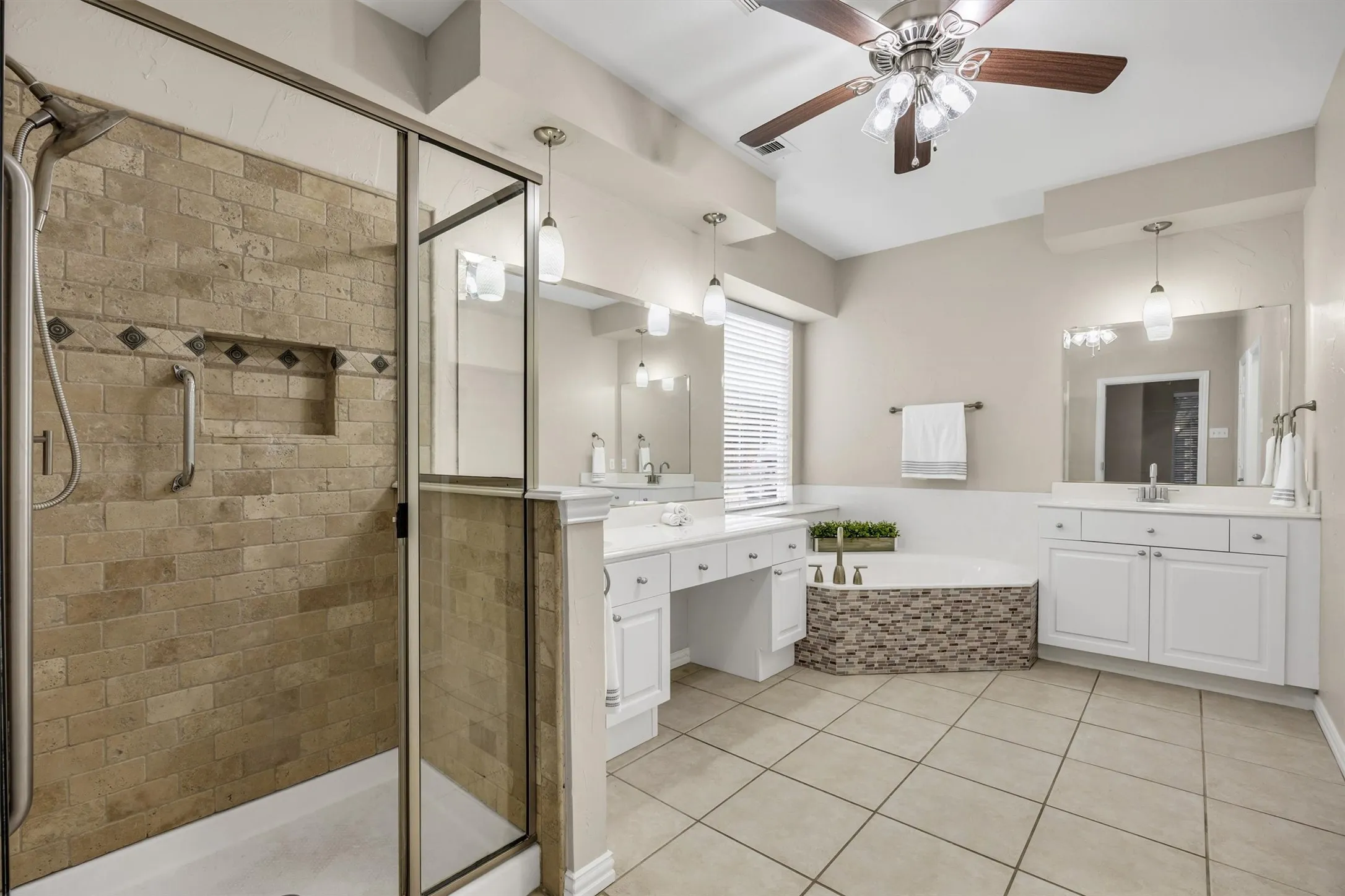 Large ensuite bathroom with a separate Glass-enclosed shower, double vanity, soaking tub with stone-look surround