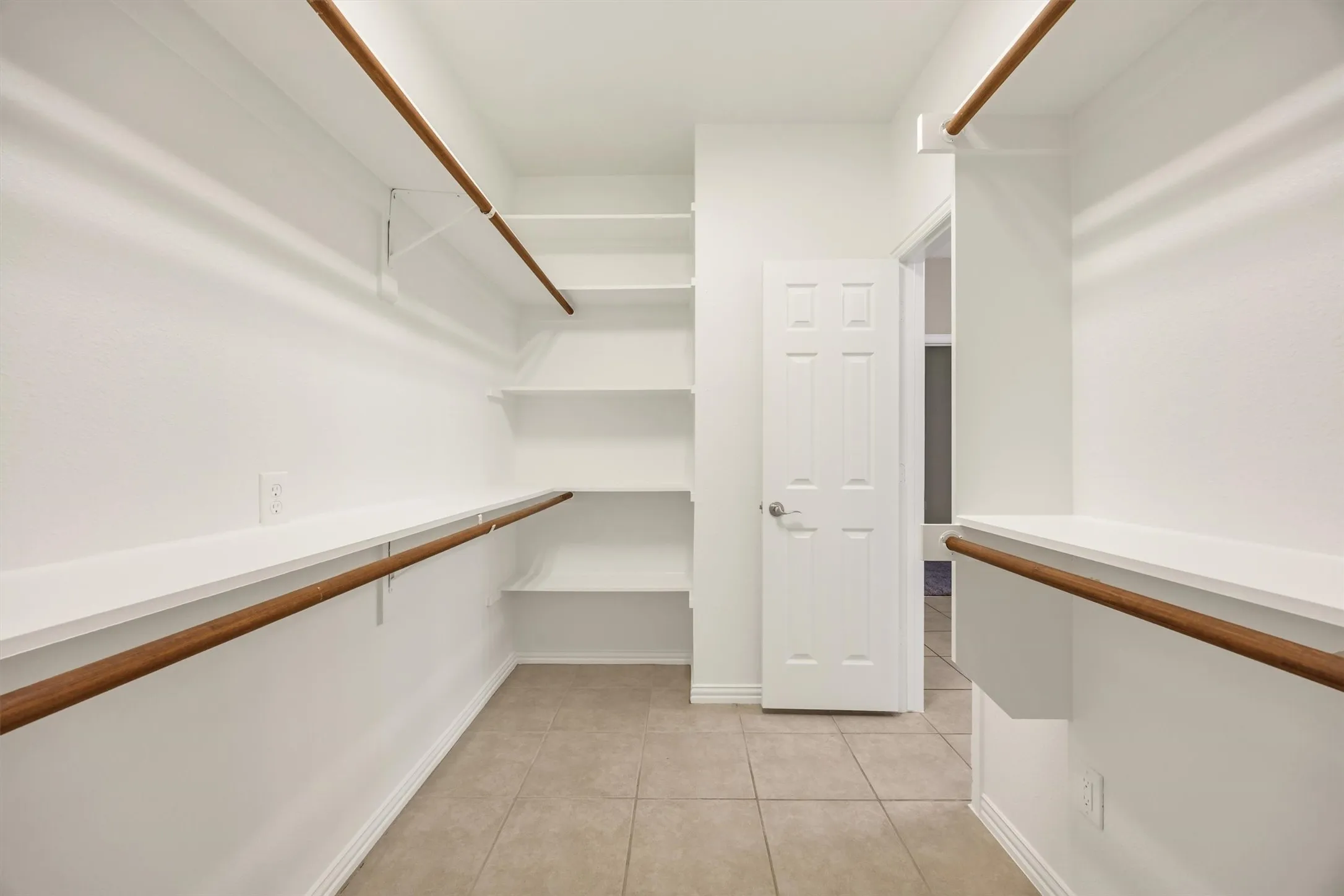 Spacious & Expansive walk-in closet featuring built-in shelving, hanging rods, and tile flooring
