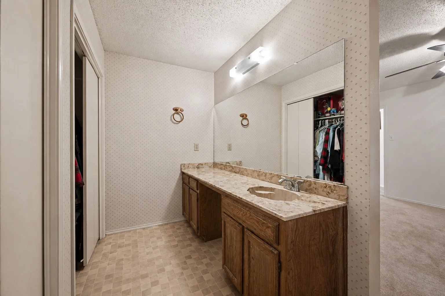 Vanity with an integrated sink, broad wall-mounted mirror, and wood-finish cabinetry