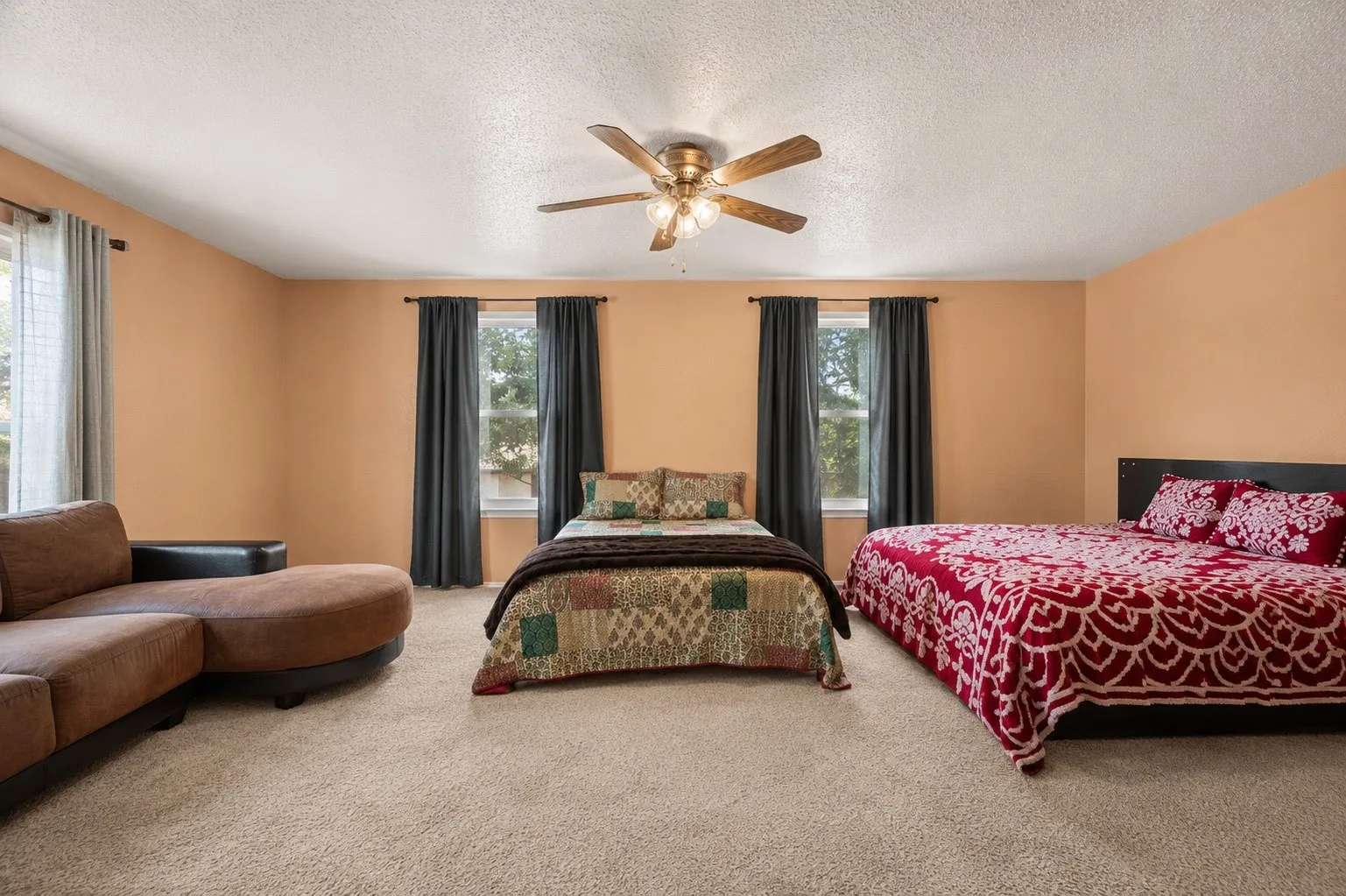 Plush carpet flooring, multiple windows, and a ceiling fan with integrated lighting