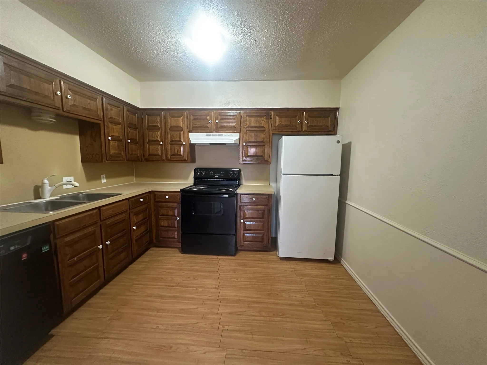 Kitchen featuring wood-finish cabinetry, a double basin sink, and wood-finish flooring