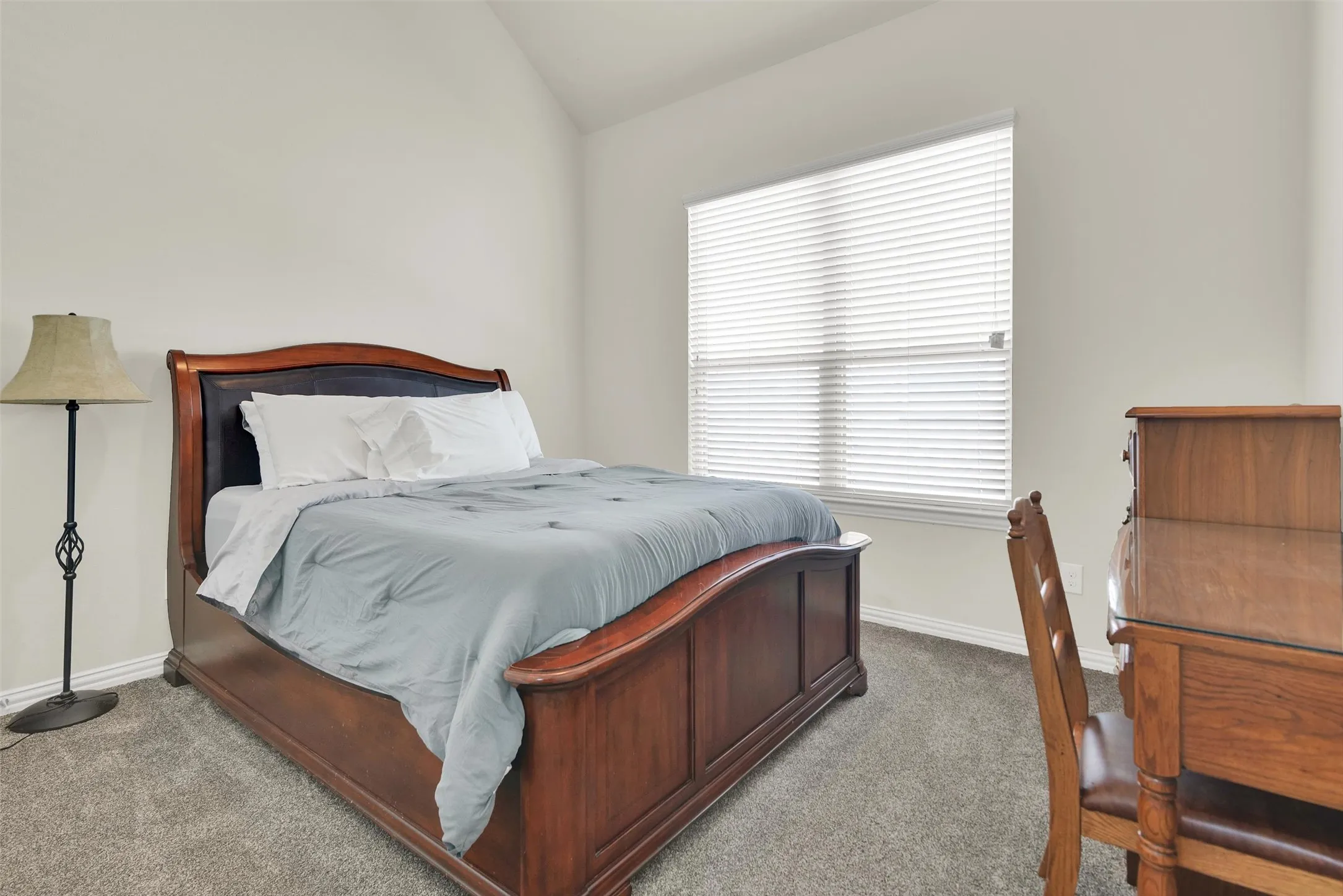 Carpeted flooring, vaulted ceiling, and window with blinds