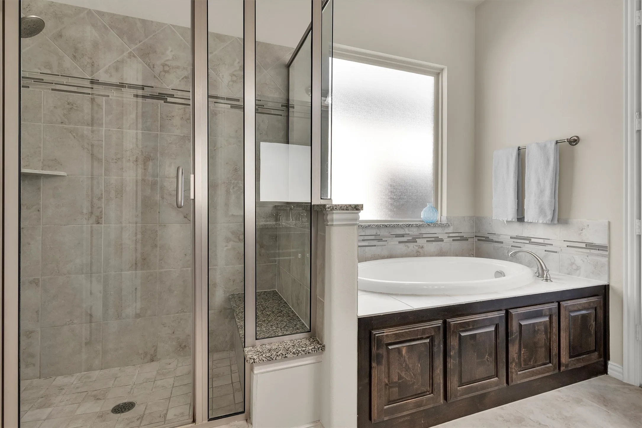 Frameless glass shower enclosure with tiled walls, built-in bench, and a rainfall showerhead
