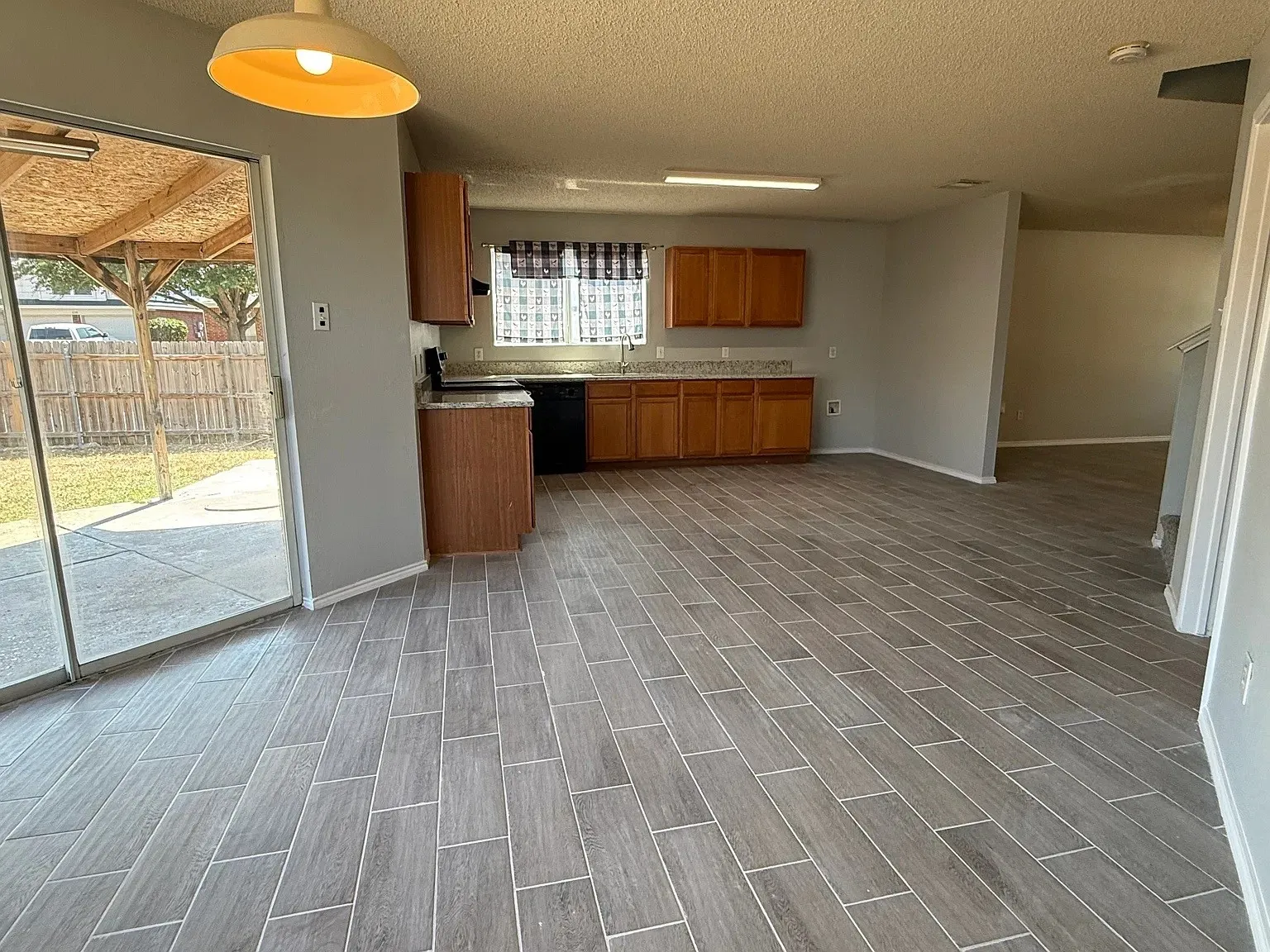 Kitchen with wood-finish cabinetry, dark countertops, and black appliances