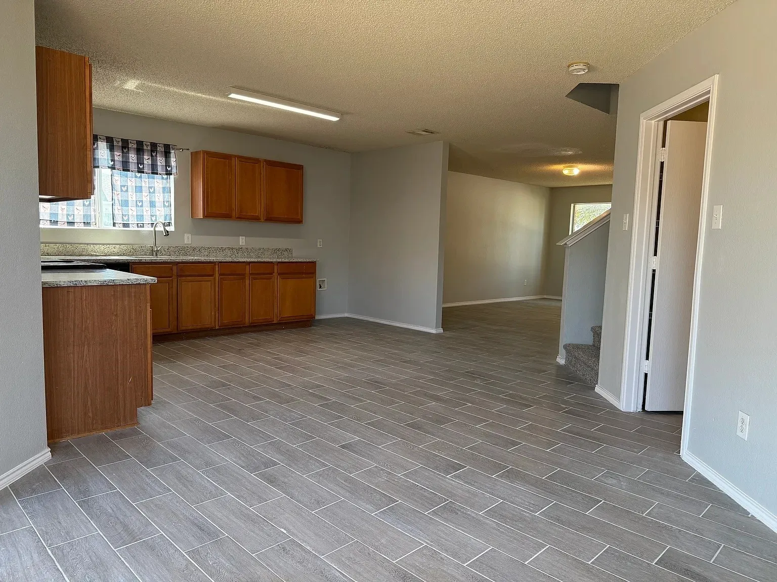 Kitchen featuring wood-finish cabinetry, granite-style countertops, and a stainless steel sink