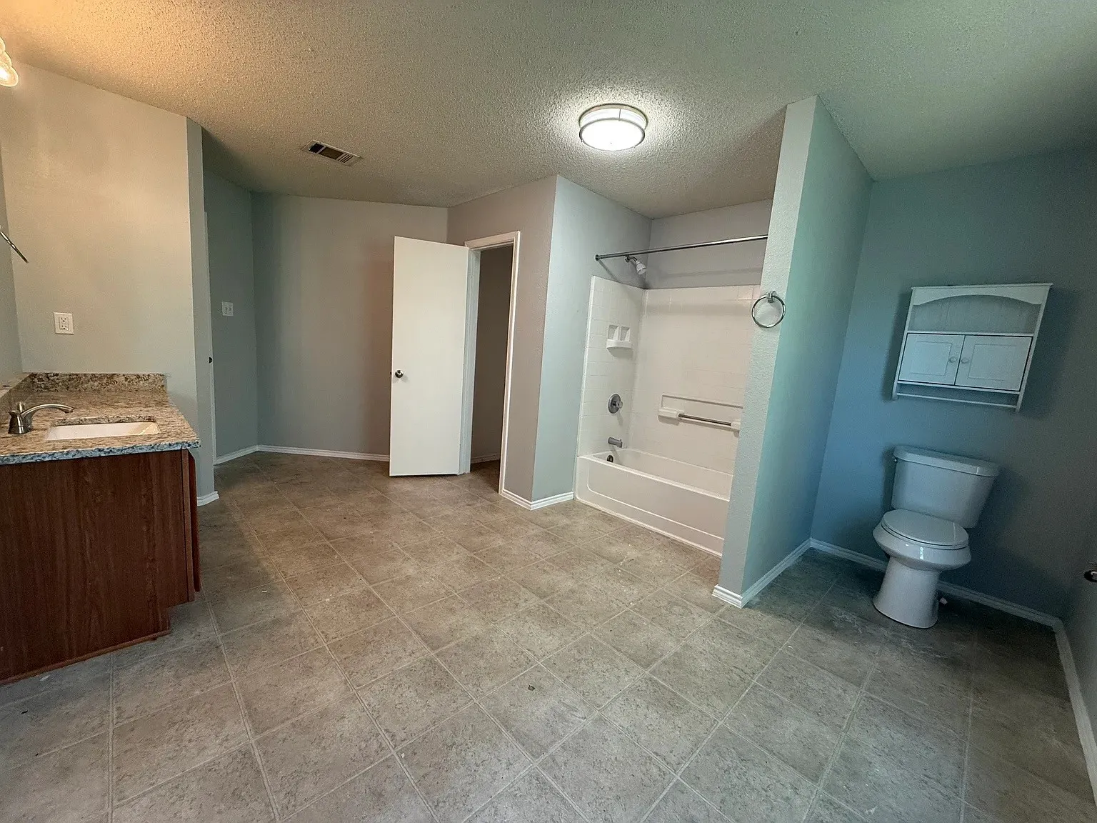 Vanity with a granite-style countertop, integrated sink, and wood-finish cabinetry