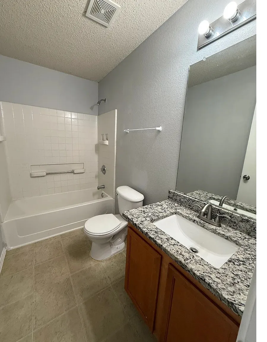 Bathroom featuring a white tub, toilet, and vanity with an integrated sink
