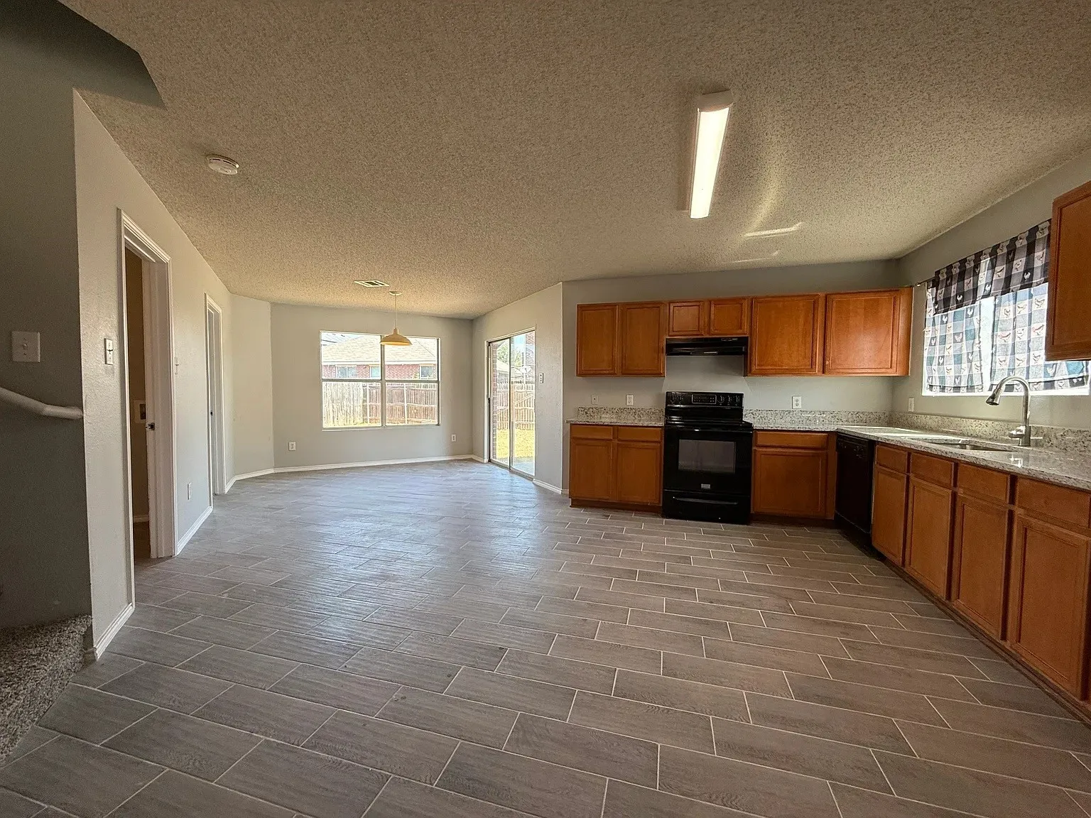 Gray tile flooring, wood cabinetry, built-in appliances, sliding glass door, and recessed lighting