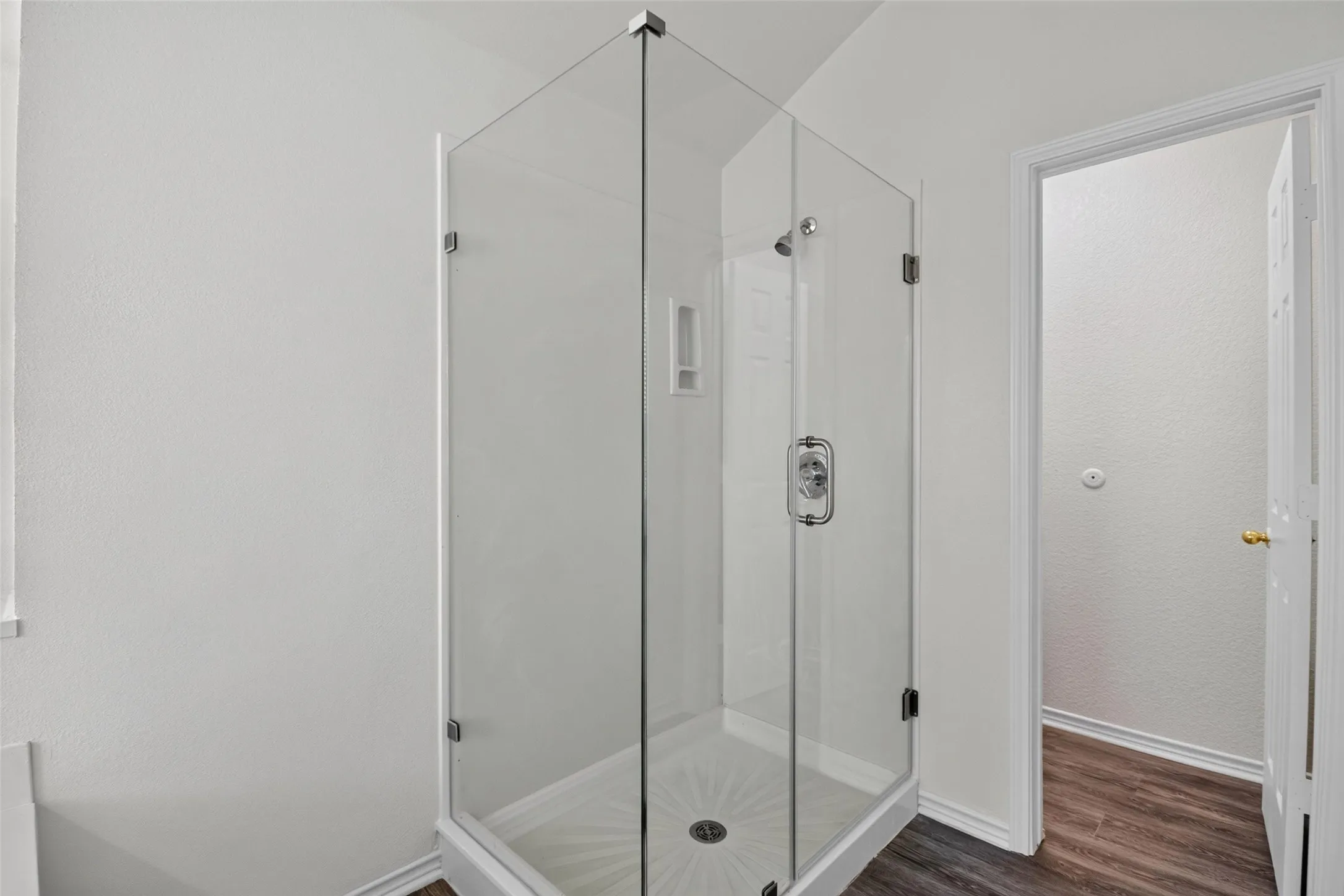 Enclosed glass shower with chrome fixtures and integrated shelving