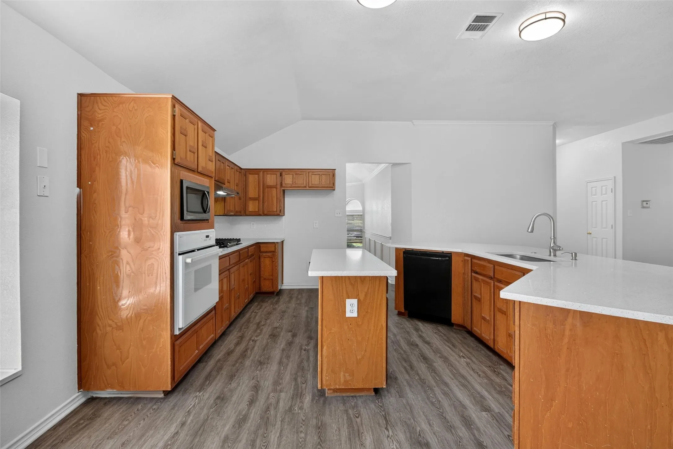 Kitchen featuring wood-finish cabinetry, white countertops, a center island, and wood-finish flooring