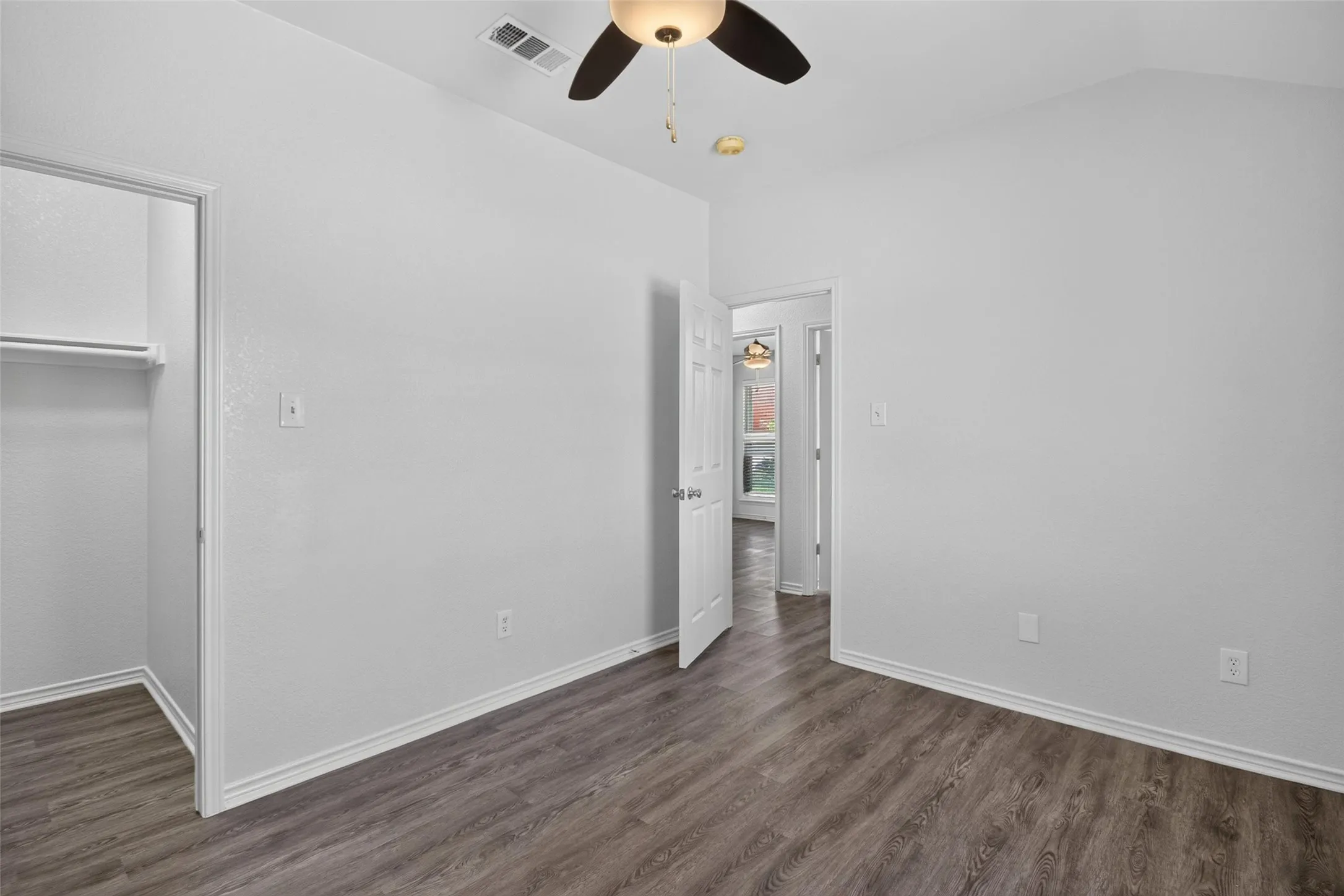 Vaulted ceiling with a ceiling fan, wood-finish flooring, and a built-in closet with shelving