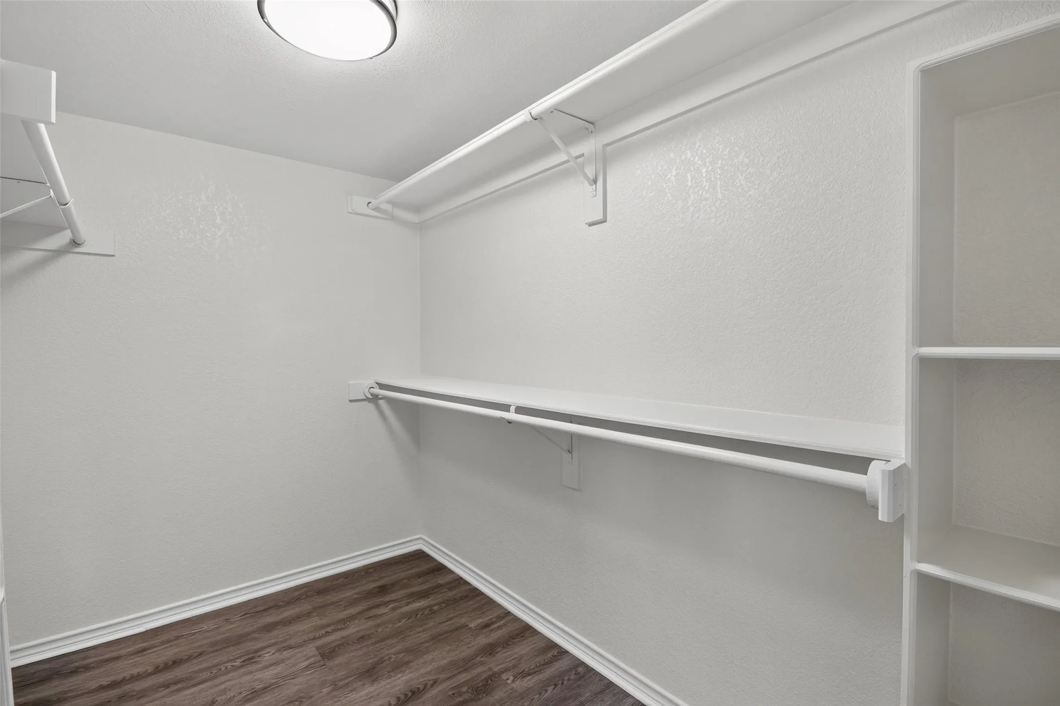 Integrated closet shelving, hanging rods, built-in storage cubbies, wood-finish flooring, and flush-mount lighting