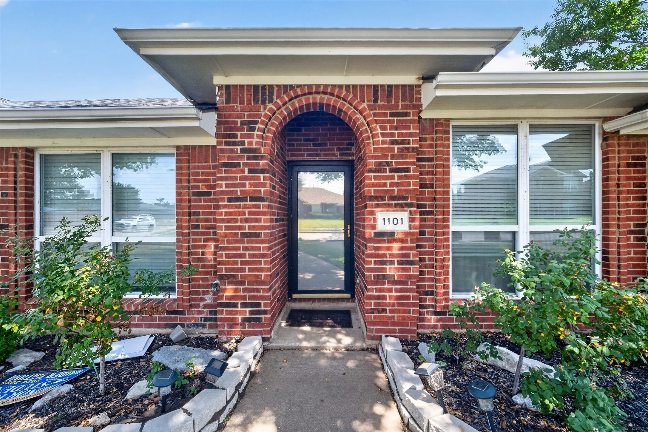 Brick facade with an arched entryway and covered porch