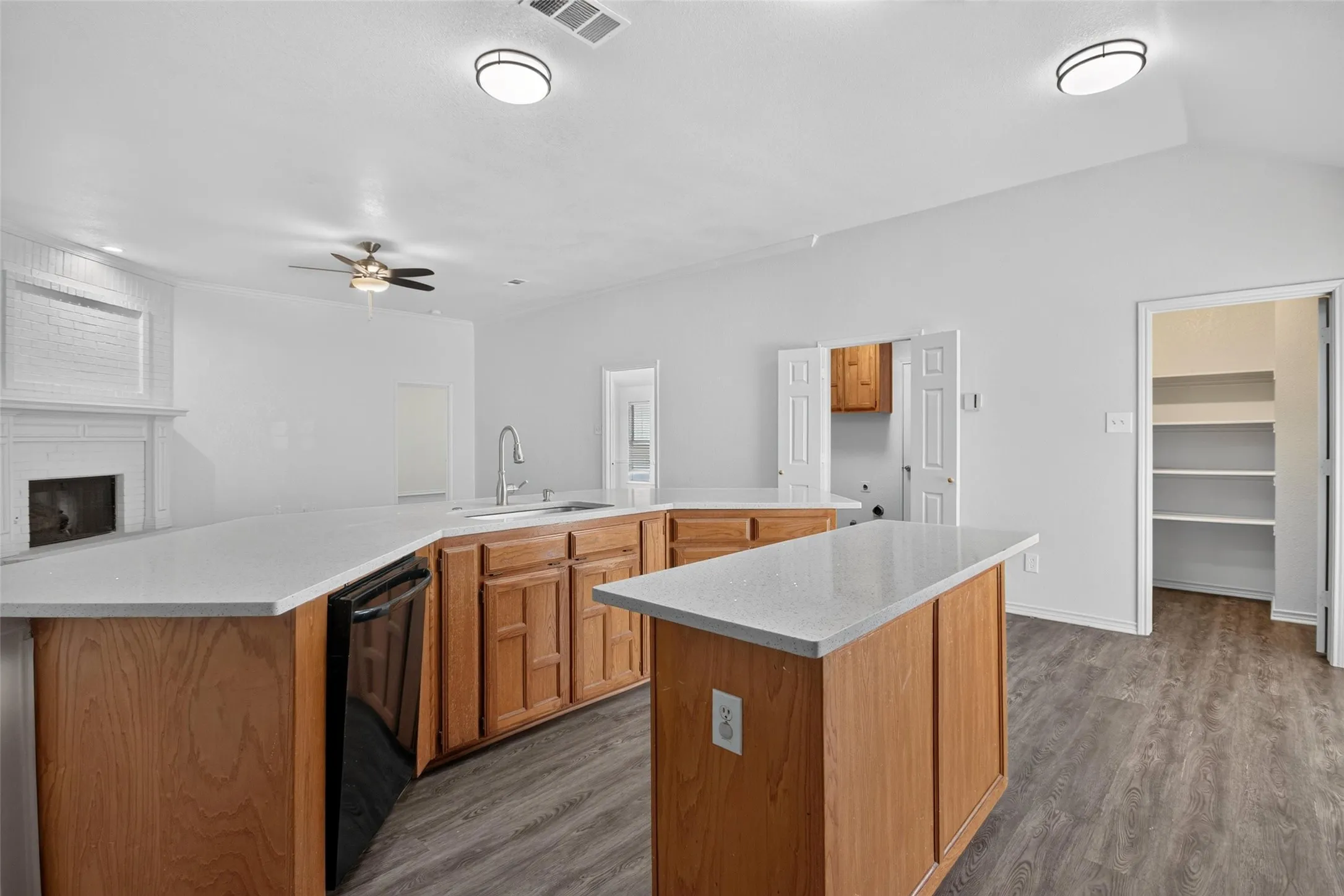 Kitchen featuring light wood cabinetry, white countertops, built-in dishwasher, and wood-finish flooring
