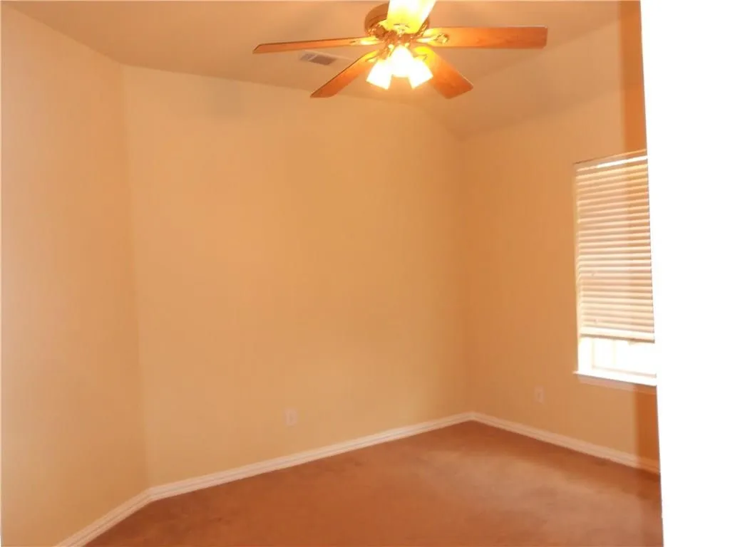 Vaulted ceiling with a wood-finish ceiling fan, carpeted flooring, and a window with horizontal blinds