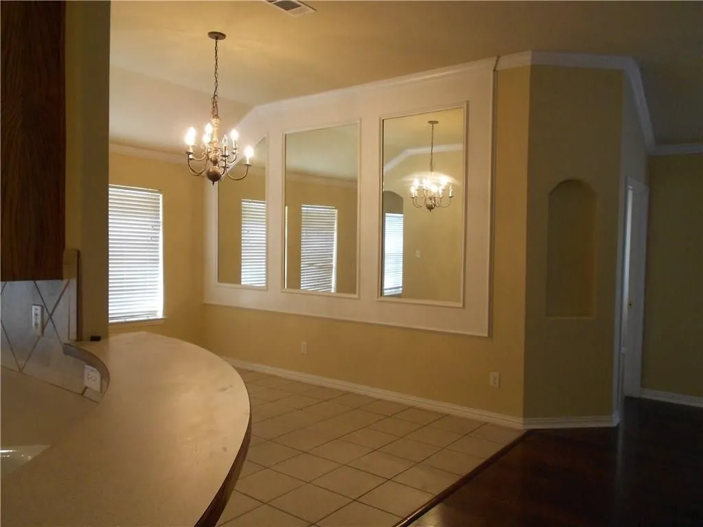Dining area featuring a chandelier, decorative wall mirrors with white trim, and a built-in arched alcove