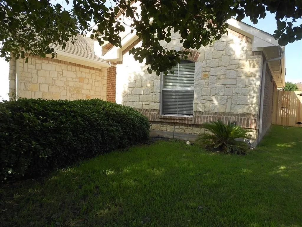 Stone and brick exterior with a pitched roofline, arched window, and established landscaping