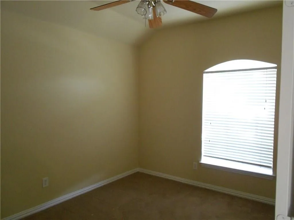 Arched window with blinds, ceiling fan with light fixture, and neutral-toned wall paint