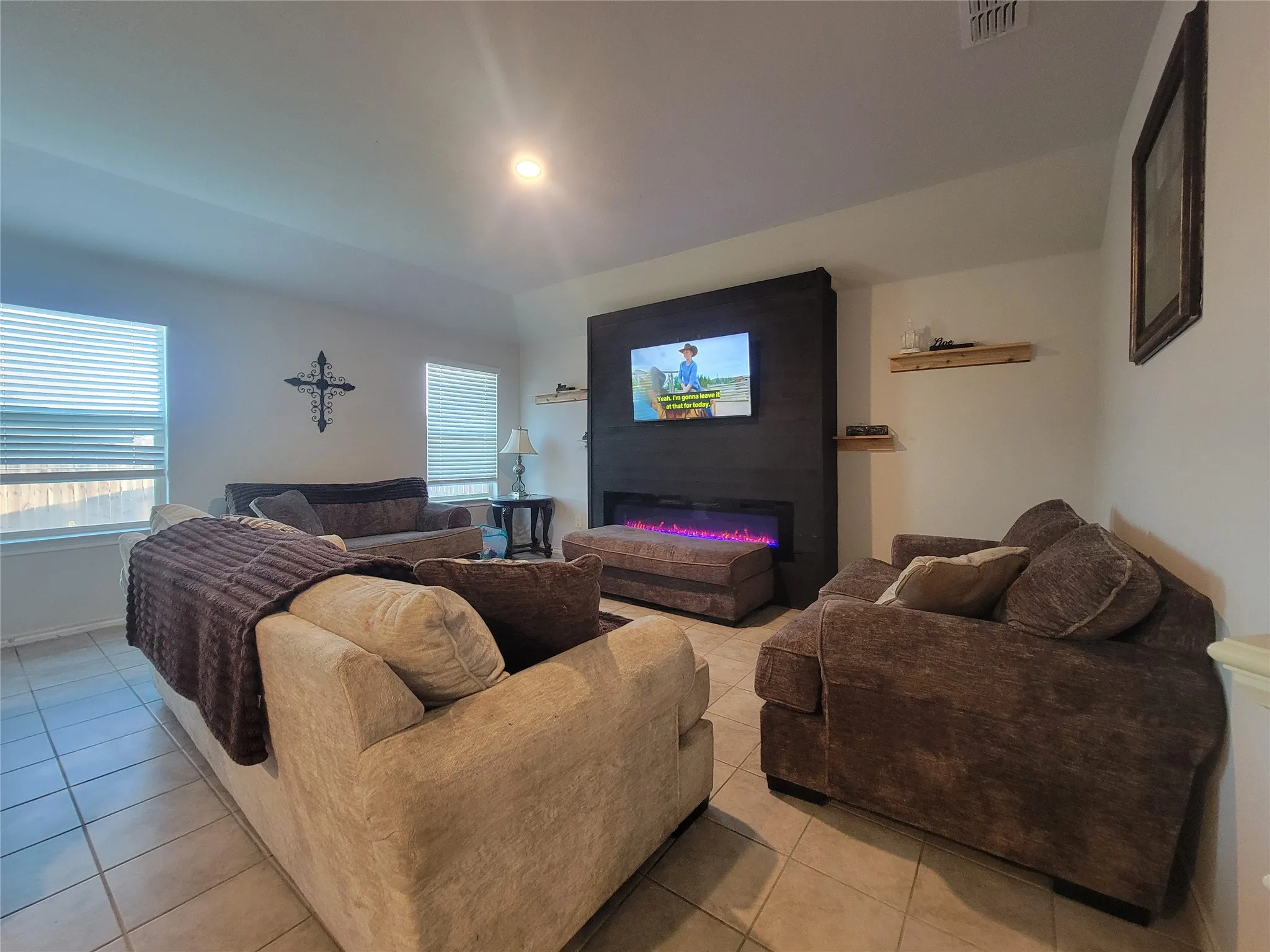 Tile flooring, recessed lighting, multiple windows, built-in electric fireplace, and floating wall shelves
