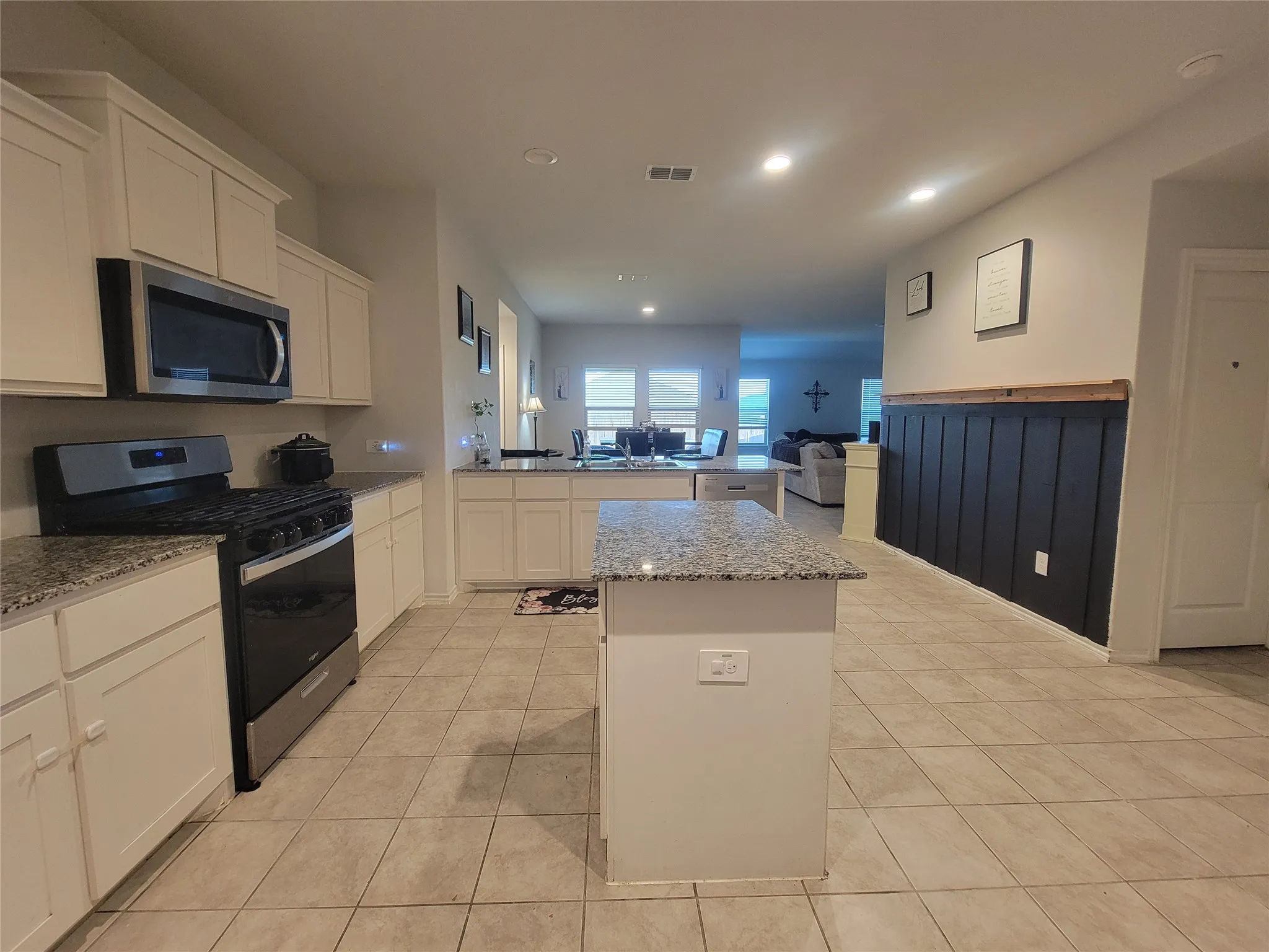 Kitchen featuring light cabinetry, granite countertops, stainless steel appliances, and tile flooring