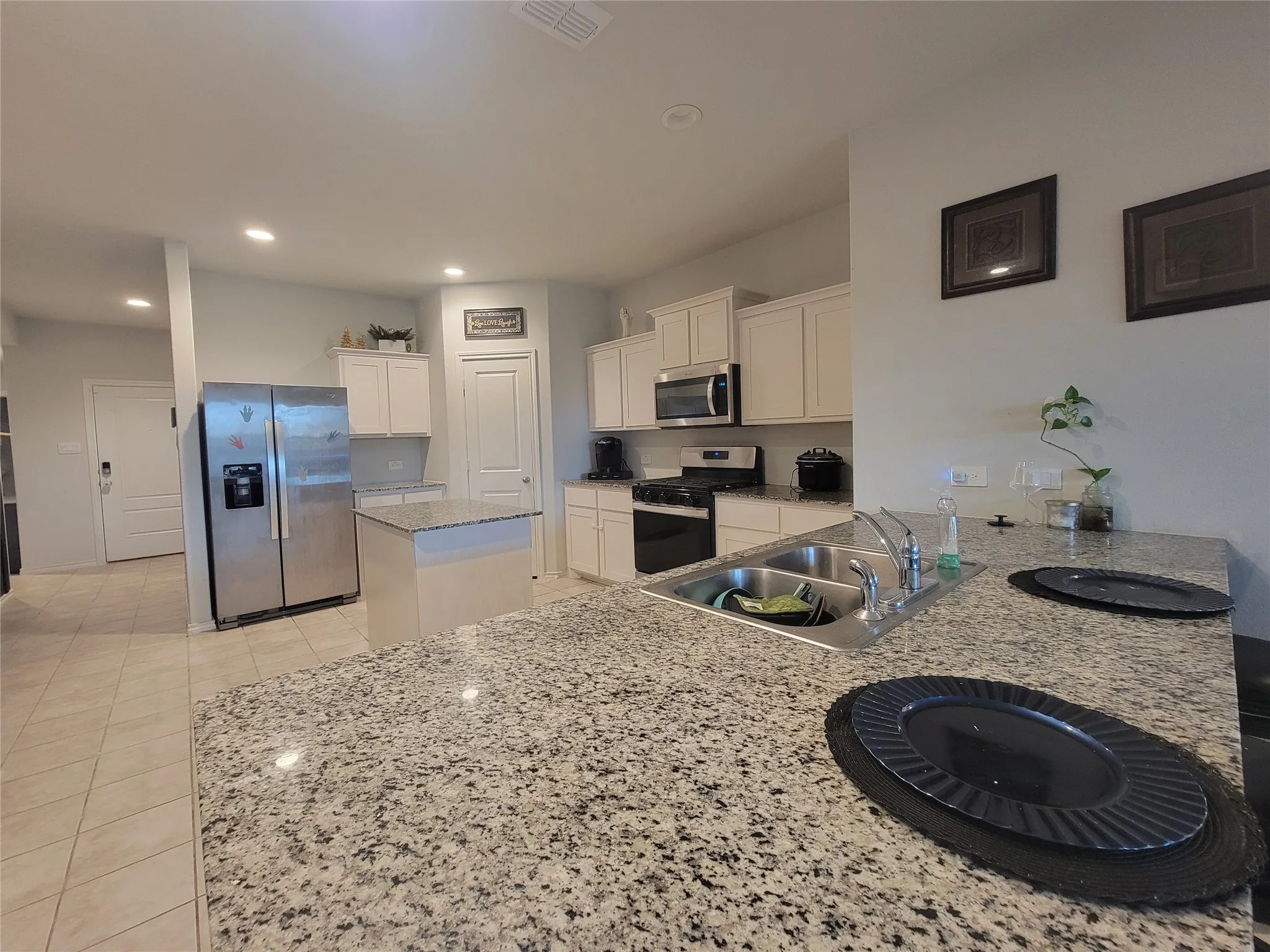 Kitchen featuring a stainless steel double-basin sink, light-toned cabinetry, light-toned countertops, and recessed lighting