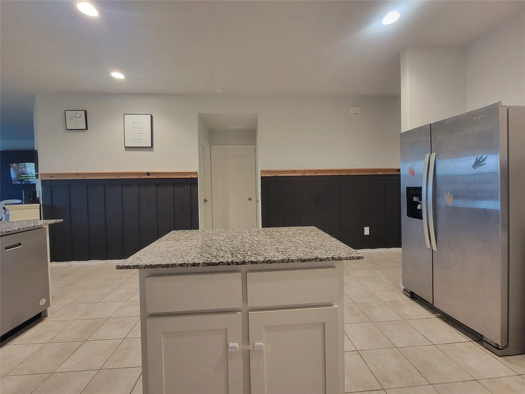 Kitchen featuring a central island with a stone-finish countertop, white cabinetry, and tile flooring