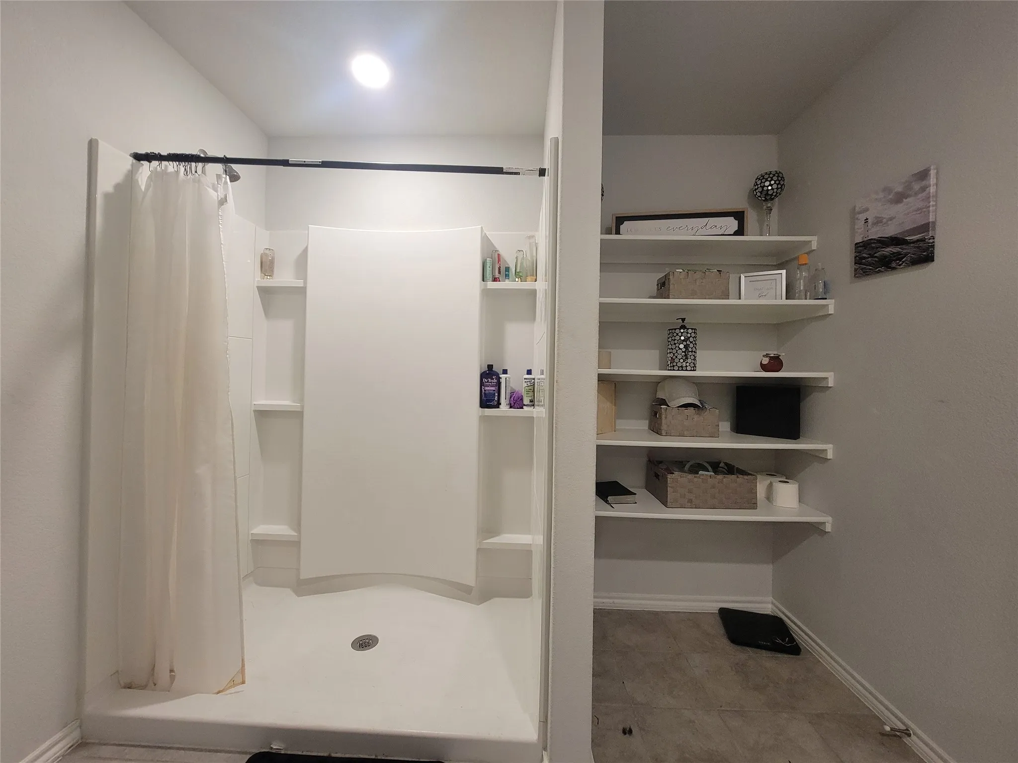 Shower stall with built-in shelving, overhead lighting, and an adjacent built-in shelving unit