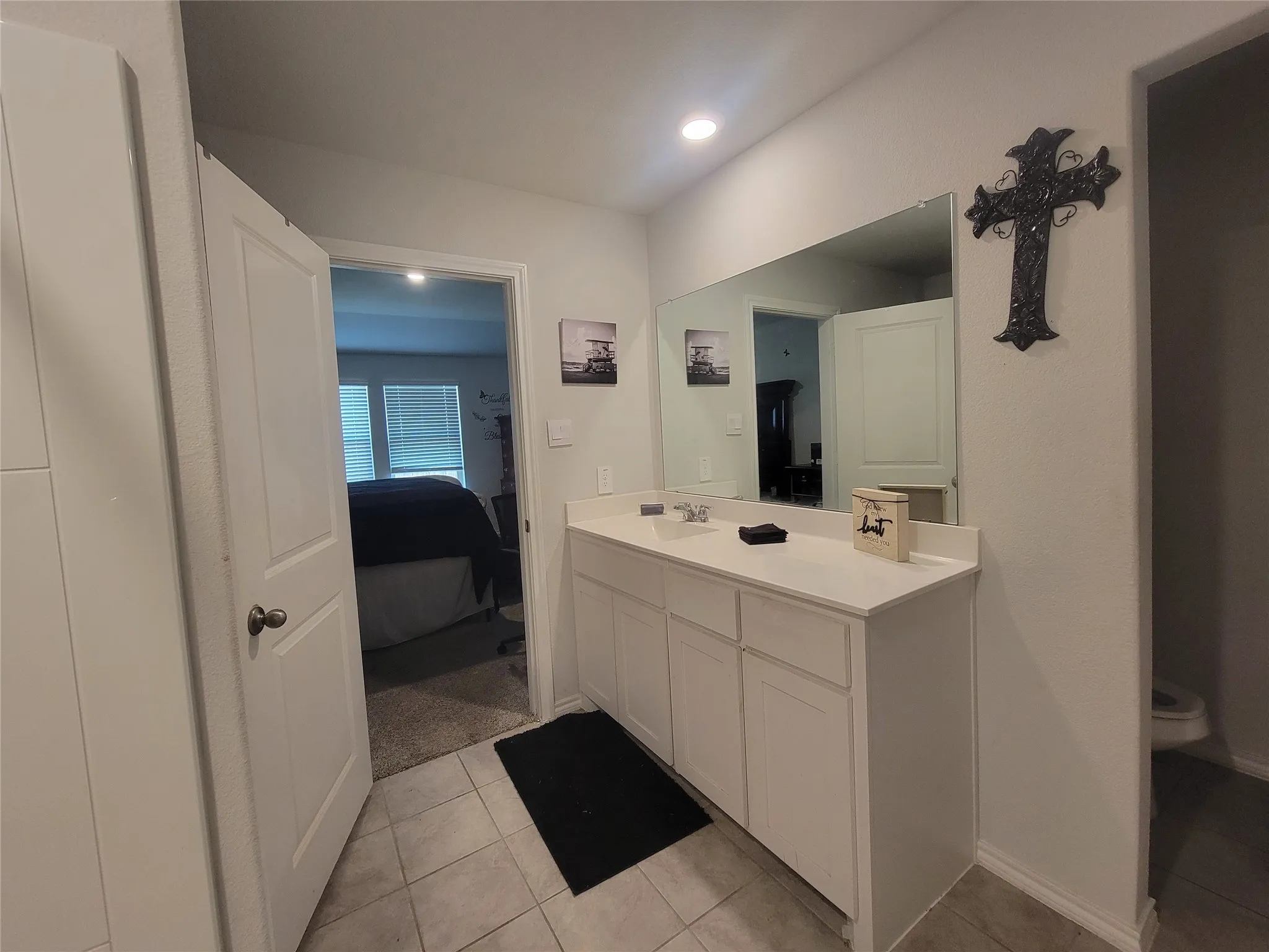 Bathroom vanity with dual sinks, a large wall-mounted mirror, and recessed lighting